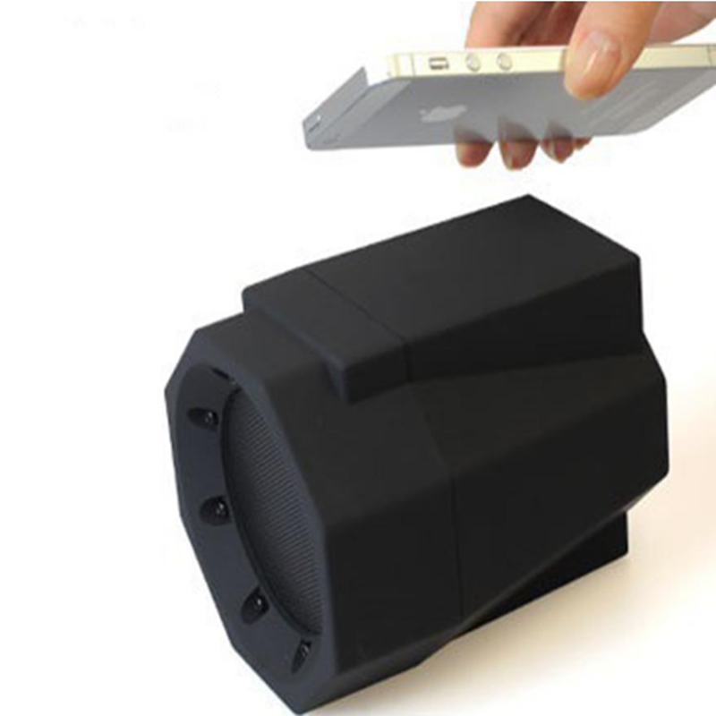 Black electronic device with a hand holding a smartphone above it on a white background