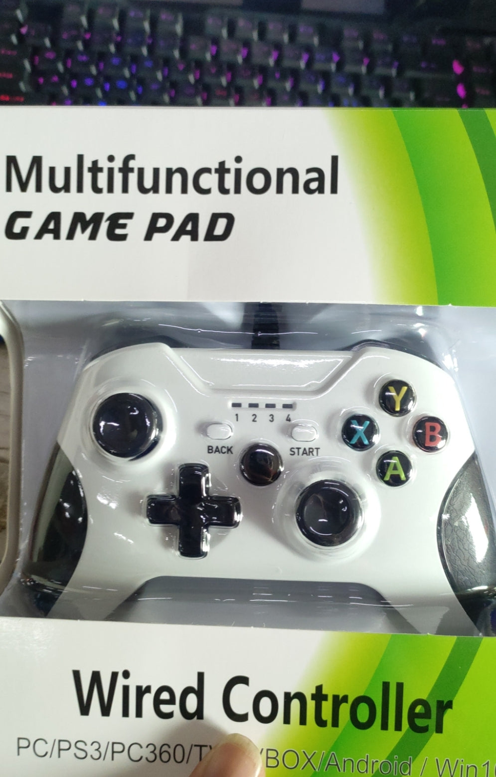 Multifunctional game pad with packaging labeled 'Wired Controller' on a blurred keyboard background.