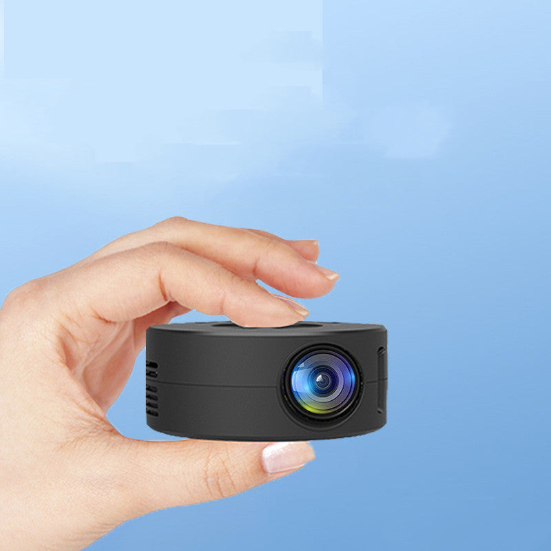 Hand holding a small black projector against a blue background