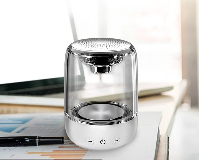 Silver and clear cylindrical lamp on a desk with a blurred background
