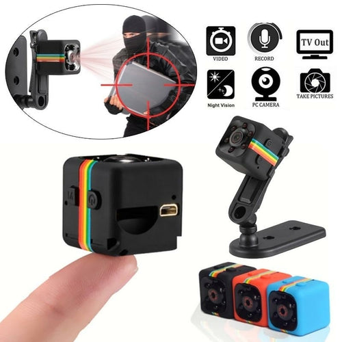 Small black camera with colorful accents, held by a hand, on a white background.